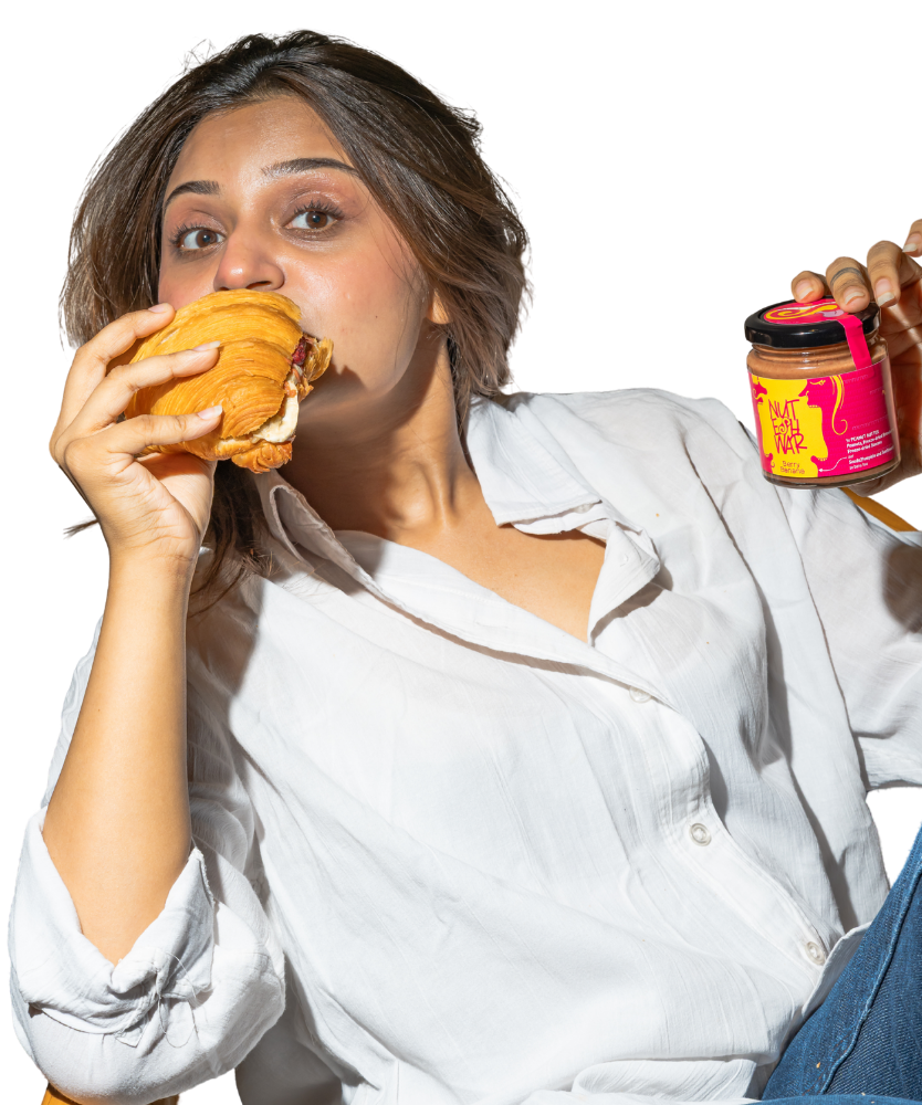 Woman eating a croissant while holding a Berry Banana Nuteshwar jar